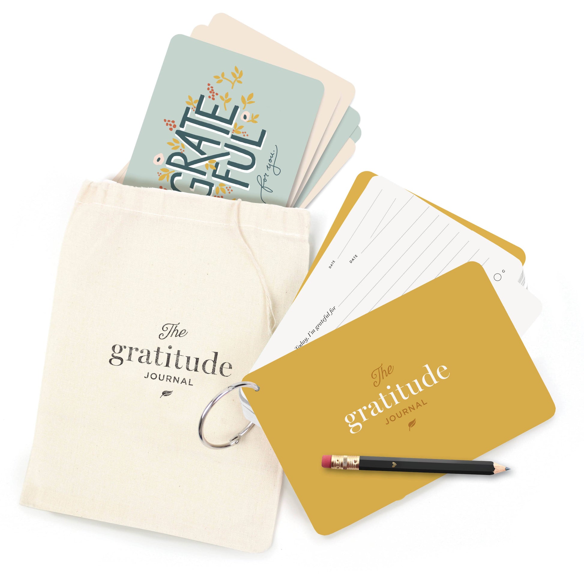 Card stock bound by a ring. The cover says "The Gratitude Journal". Accompanied by a small canvas bag to hold the journal and cards with the words "Grateful" on the back.