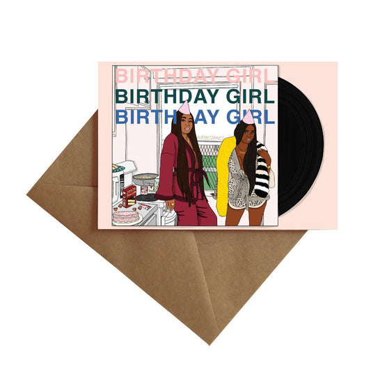 Birthday girl written three times with drawing of two beautiful black women wearing loungewear, birthday hats, and standing in a kitchen decorating a cake.